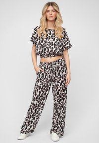Sada loungewear so zvieracím vzorom kožešiny leopardov obsahuje skrátený top so širokými rukávmi a nohavice s vysokým pásom a voľným strihom. Jemný materiál s hladkou textúrou.