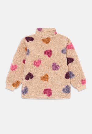 Fleece genser i beige med en myk, teksturert overflate. Har fargerike hjerte mønstre i rosa, lilla, brun og mørk lilla. Høy krage design.
