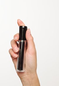 Schwarze und transparente Glasserumflasche, die in einer Hand gehalten wird, mit einem schwarzen Deckel und silbernem Akzent. Das Etikett lautet "Aktivierungsserum."
