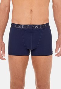 Marinblå herrboxer med mjuk midja som har vitt logotext; slät textur och en åtsittande design med en frontficka.