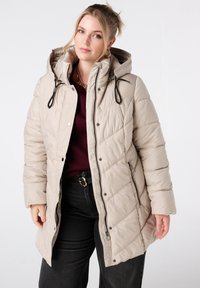 Licht beige gewatteerde pufferjack met capuchon, trekkoorden en ritssluiting aan de zijkanten. Voorzien van een ruitpatroon en knoopsluiting.