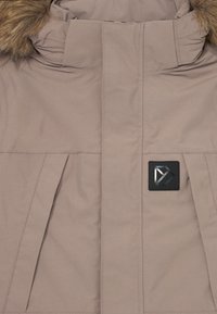 Cappotto inverno beige con cappuccio bordato in pelliccia, zip frontale nascosta da una pattina, tasche inclinate e un logo quadrato nero sul petto.
