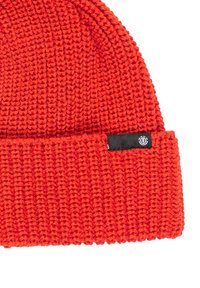 Czerwona dzianinowa czapka beanie z grubego włóczki, z podwiniętym brzegiem i małą czarną metką z logo.
