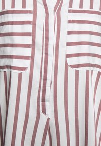 Camicia a righe in bianco e rosa polveroso, caratterizzata da una vestibilità ampia, due tasche sul petto, un'apertura verticale con bottoni e una texture di tessuto leggera.