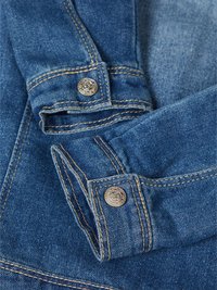 Denimjakke mansjett med en blå tekstur, gullsøm og sølvknapper med et preget mønster.
