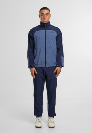 Granatowa sportowa kurtka z jasnoniebieskimi akcentami; posiada zamek błyskawiczny, stojący kołnierz i elastyczne mankiety, w zestawie z pasującymi spodniami.