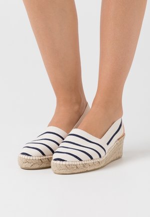 Zapatos de cuña de esparto a rayas en lona color crema y azul marino, con detalles de yute trenzado y diseño de punta cerrada.