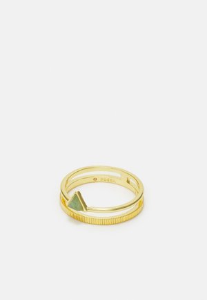Anillo de metal de color dorado con una banda delgada, detalle en el borde con textura y un pequeño detalle de piedra verde triangular en el frente.