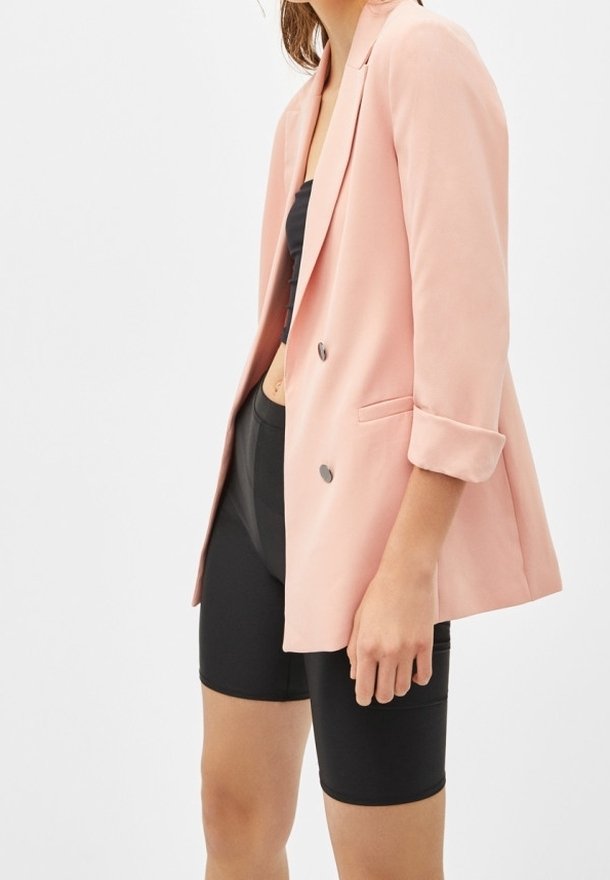 Rosa kavaj i blush-färg med en skräddarsydd passform, enfärgad design, uppvikt ärm och subtila glänsande knappar. Matchad med svarta cykelshorts.