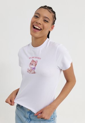 Hvid bomulds t-shirt med et cartoon katte-grafik, der har en lilla sløjfe og teksten "ikke din kat." Korte ærmer, slim-fit design.