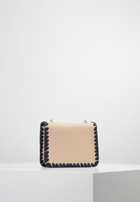 Borsa in pelle beige con bordi scallop in blu navy e hardware dorato. Forma rettangolare, texture liscia e dimensioni compatte.