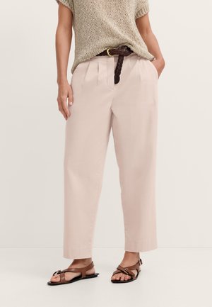 Person wearing beige wide-leg pants with pleats, a brown braided belt, a loose knit beige sweater, and brown strappy flat sandals.