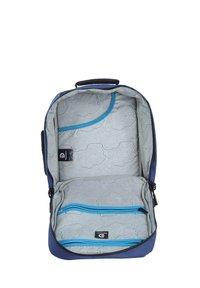 Interior de mochila marina con patrón geométrico gris claro, acentos azules, bolsillo de malla y un compartimento con cremallera para almacenamiento organizado.