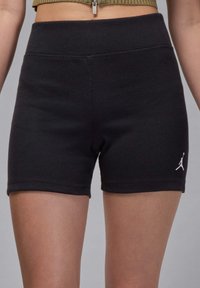Svarta ribbade shorts med hög midja, med en vit Jumpman-logotyp på den nedre vänstra sidan. Mjuk textur, åtsittande design.