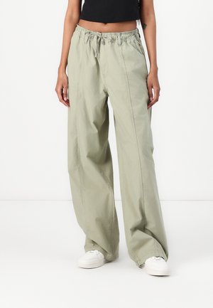 Light green, wide-leg pants made from a soft, lightweight fabric. Features an elastic waistband with drawstring and visible seam details.