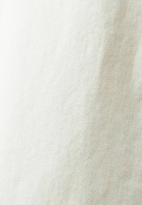 Gros plan d'un tissu beige montrant une fine texture tissée et des plis diagonaux subtils.