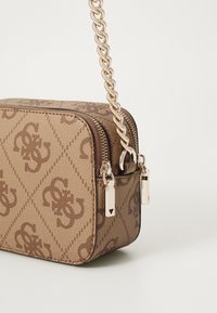 Borsa a tracolla marrone con motivo, superficie testurizzata, tracolla in metallo dorato e chiusure zip dettagliate. Forma rettangolare compatta.