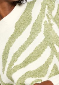 Suéter de punto con un patrón de rayas de cebras en verde y blanco. Material Texturizado con un acabado suave y peludo, y un cuello acanalado.