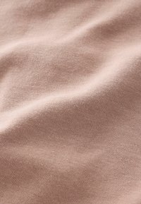 Tissu en coton rose clair avec une texture lisse et un léger stretch, présentant un motif en maille fine et un drapé doux.