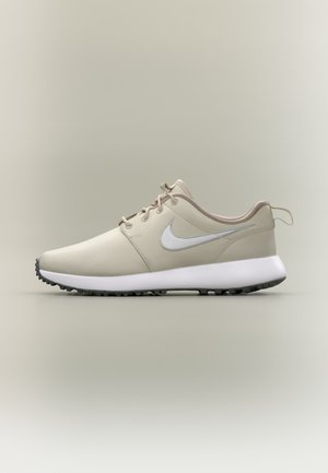 Μπεζ αθλητικό παπούτσι Nike με λευκή σόλα και γκρι λογότυπο swoosh, χαμηλή σχεδίαση, κλείσιμο με κορδόνια και υφή μαύρης εξωτερικής σόλας.
