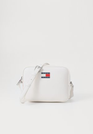 Bolsa transversal sintética branca com forma retangular, alça ajustável e um pequeno rótulo de logotipo com detalhes em vermelho e azul.