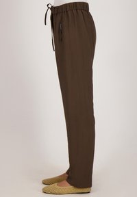 Bruine, lichte broek met een trekkoordtaille, voorzien van een gladde structuur en een recht model, gecombineerd met lichtgekleurde flats.