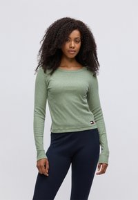 Groene langemouwen shirt van gestructureerde stof met een ronde hals. Gecombineerd met donkerblauwe leggings met subtiele naaddetails.