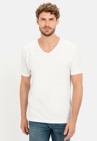 Hvid bomulds V-hals t-shirt med korte ærmer, glat tekstur og en afslappet pasform, parret med blå denim jeans. Ingen mønstre eller accenter.