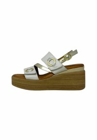 Sandali wedge bianchi e dorati con due cinghie incrociate e una fibbia, dotati di una suola piattaforma marrone con texture.