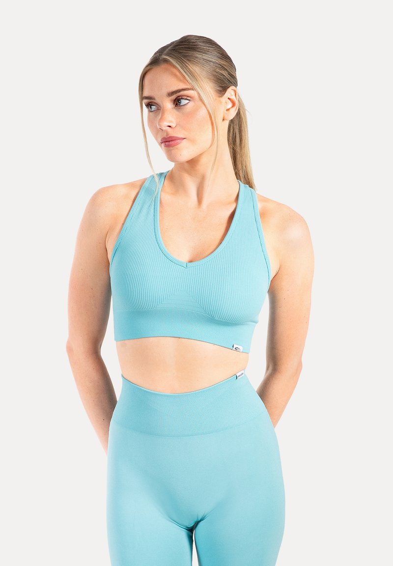 Sujetador deportivo azul claro con textura acanalada, escote redondo y tirantes anchos, combinado con leggings a juego de cintura alta que tienen un detalle recortado.