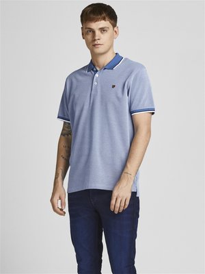Camisa polo de color azul claro con un patrón texturizado, tapeta de dos botones y cuello de color azul oscuro en contraste. Llevarla con jeans de color azul oscuro.