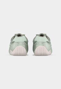 Paire de baskets vert menthe et grises avec des semelles rose pâle, vues de dos sur un fond blanc.