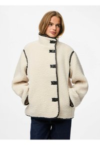 Kremfarget fleecejakke med høy krage, svarte knappedetaljer og kontrastsøm. Løs passform med to sidelommer.