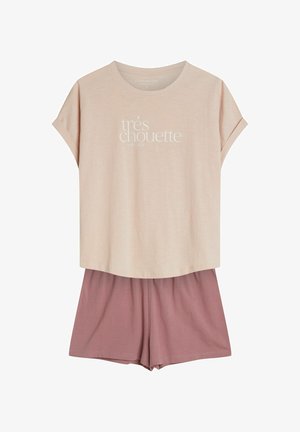 Jasnoróżowa koszula z krótkim rękawem z napisem "trés chouette very nice" w zestawieniu z luźnymi szortami w stonowanym odcieniu róży.
