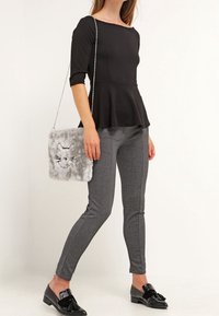 Černý peplum top, šedé slim kalhoty a černé polobotky. Šedá plyšová taška ve tvaru kočky s vyšívanými detaily. Stříbrný řetízek.