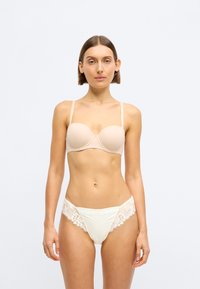 Goličasti grudnjak bez podstave s tankim naramenicama uparen s bijelim gaćicama s čipkastim leđima, s cvjetnim čipkastim detaljima i glatkom teksturom.