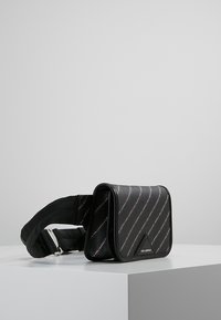 Borsa a tracolla nera con motivo a strisce diagonali argento, materiale testurizzato, accento con logo triangolare e tracolla in tessuto regolabile.
