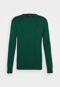 Grön stickad tröja med långa ärmar, rund halsringning och en liten logotyp på bröstet. Slät textur, inga mönster och medelhållig passform.