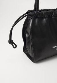 Borsa in pelle nera con parte superiore arricciata e chiusura con cordoncino. Presenta una texture liscia e un logo visibile stampato in bianco.