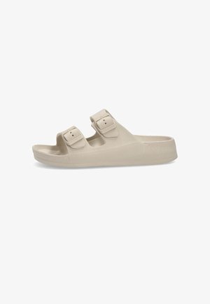 Sandalias de un ligero color beige con dos correas ajustables de hebilla, hechas de un material sintético texturizado, con una suela plana y puntera redondeada.