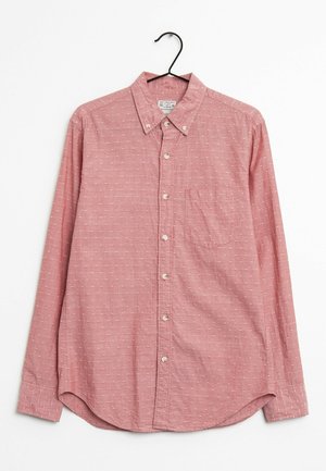 Camisa roja de botones con una tela texturizada, pequeños patrones blancos, cuello, mangas largas y un solo bolsillo en el pecho. Cuelga de un gancho negro.