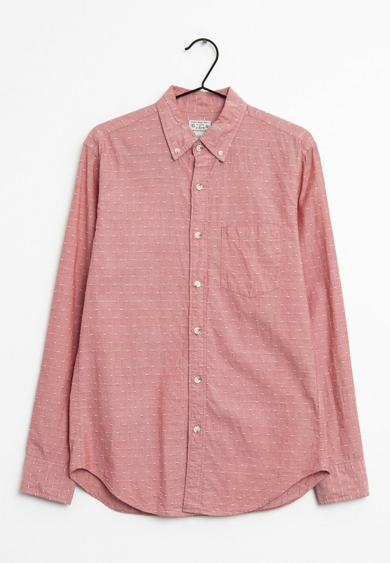 Chemise rouge à boutons avec un tissu texturé, petits motifs blancs, col, manches longues, et une poche poitrine. Accrochée à un crochet noir.