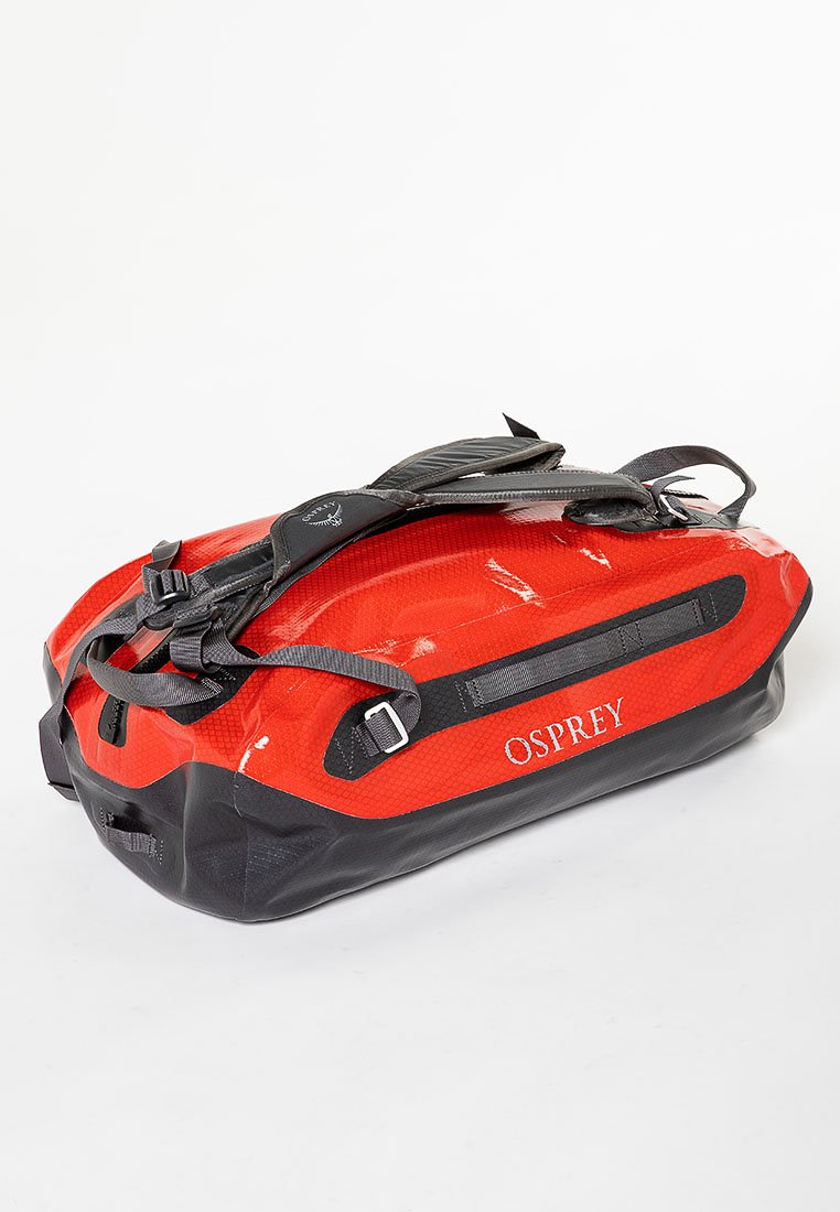 Borsa a duffel impermeabile Osprey rossa e nera con spallacci regolabili e chiusure a fibbia, mostrata su uno sfondo bianco.
