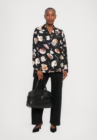 Black button-up shirt with a food-themed print, paired with high-waisted black trousers and a structured black handbag.