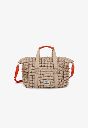 Beige quilted nylon duffel bag with red faux leather handles and adjustable strap. Features a front pocket and textured body.