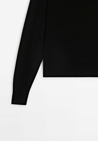 Pull noir à manches longues en maille avec un ourlet droit, présenté sur un fond blanc, mettant en avant la manche gauche et la partie inférieure du torse.