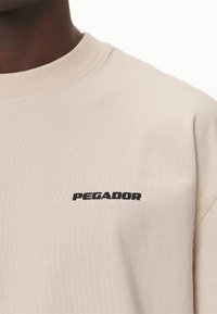 Pegador LOGO TEE - T-shirt basic - washed desert sand/black gum