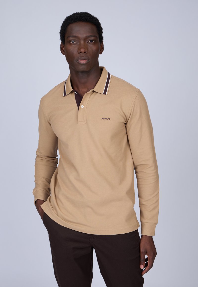Polo à manches longues beige avec un col marron foncé et des détails rayés subtils, présentant un petit logo brodé sur la poitrine.