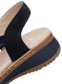 Sandalia de cuña de ante negro con plantilla acolchada beige, tiras elásticas y suela texturizada marrón y negra, mostrada en primer plano.