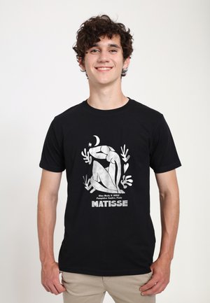 Czarny bawełniany t-shirt z białą grafiką inspirowaną "Niebieską Nagością II" Matisse'a, z organicznymi kształtami i wyrazistym tekstem.